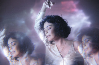 An image has been taken with a dreamy filter or a woman dancing in light purple lights. The filter refractions mean a mirror image of her appears on each side. 