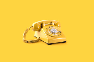 On a bright yellow background sits a yellow rotary phone.