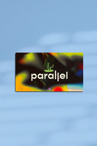 Parallel gift card appears on a sky blue background. The card features a space gradient texture with black, green, yellow and red colours and the stacked Parallel logo in green and cream